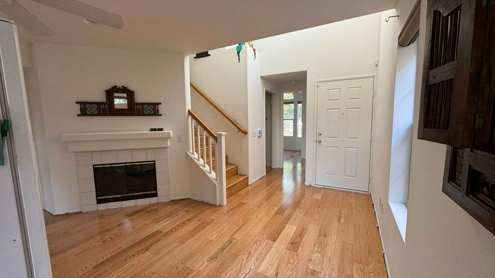 A living room with hardwood floors , a fireplace and stairs.